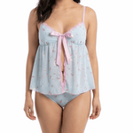 Woman wearing a light blue lace nightgown with a pink bow on a white background