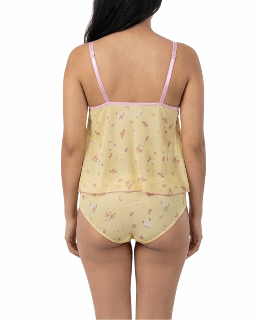 Woman wearing a yellow floral nightgown with pink straps on a white background