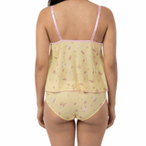Woman wearing a yellow floral nightgown with pink straps on a white background