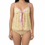 Woman wearing a yellow floral nightgown with pink trim on a white background
