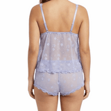 Woman wearing a sheer floral top and shorts set on a white background