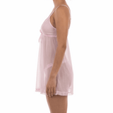 Woman wearing a light pink slip dress against a white background