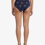 Rear view of a model wearing high-waisted navy blue bikini bottoms with a gold star pattern, shown against a plain white background.