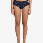 A model is shown from the waist down wearing navy blue bikini bottoms with a gold star pattern, set against a plain white background.