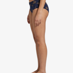 Side view of a model wearing navy blue bikini bottoms with a gold star pattern, shown against a plain white background.