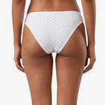 White bikini bottom with small black polka dots, shown on a model against a light gray background.