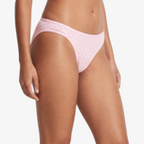 Pink bikini bottom with small brown polka dots, shown on a model against a light gray background.