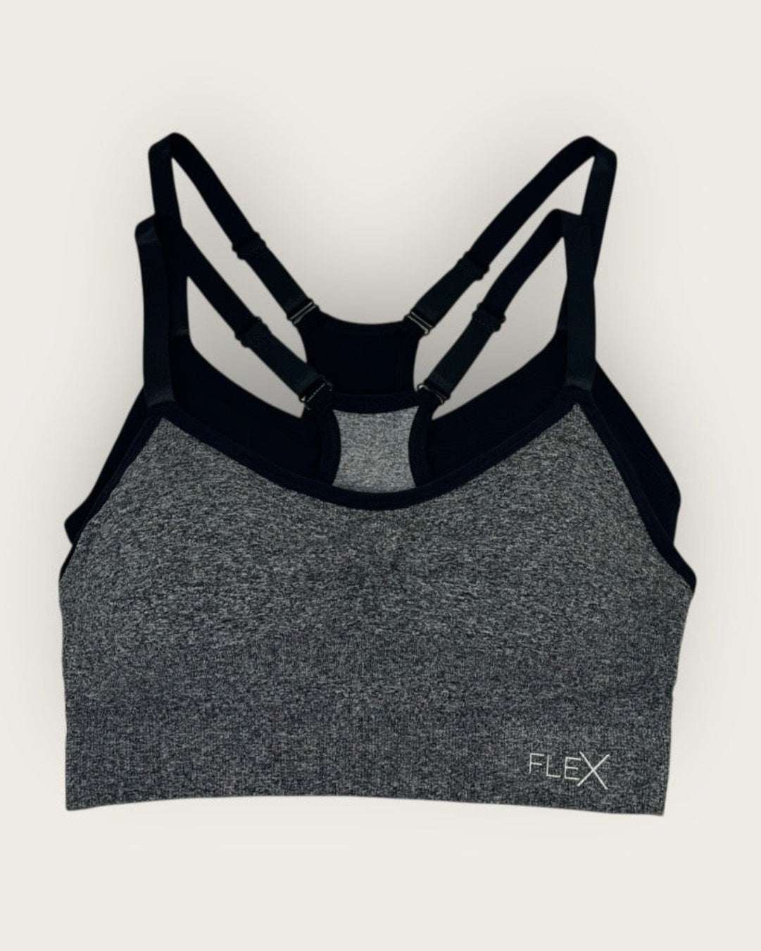 Gray sports bra with black straps on a white background
