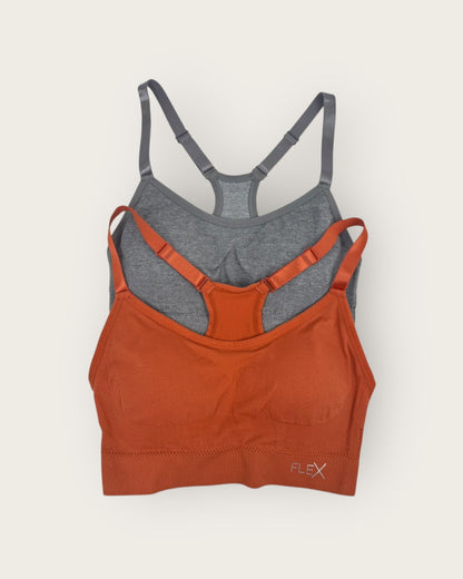 Two sports bras, one orange and one gray, on a light beige background.