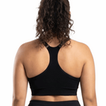 Woman in a black sports bra against a white background.