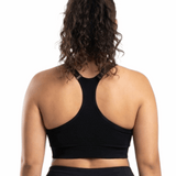 Woman in a black sports bra against a white background.