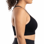 Woman in a black sports bra against a white background.
