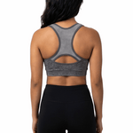Woman wearing a gray sports bra and black leggings on a white background