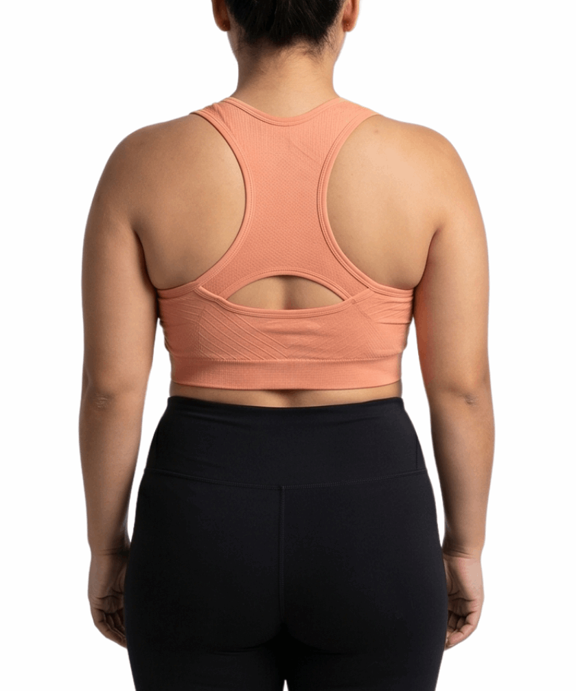 Person wearing a peach sports bra and black leggings on a white background