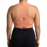 Person wearing a peach sports bra and black leggings on a white background