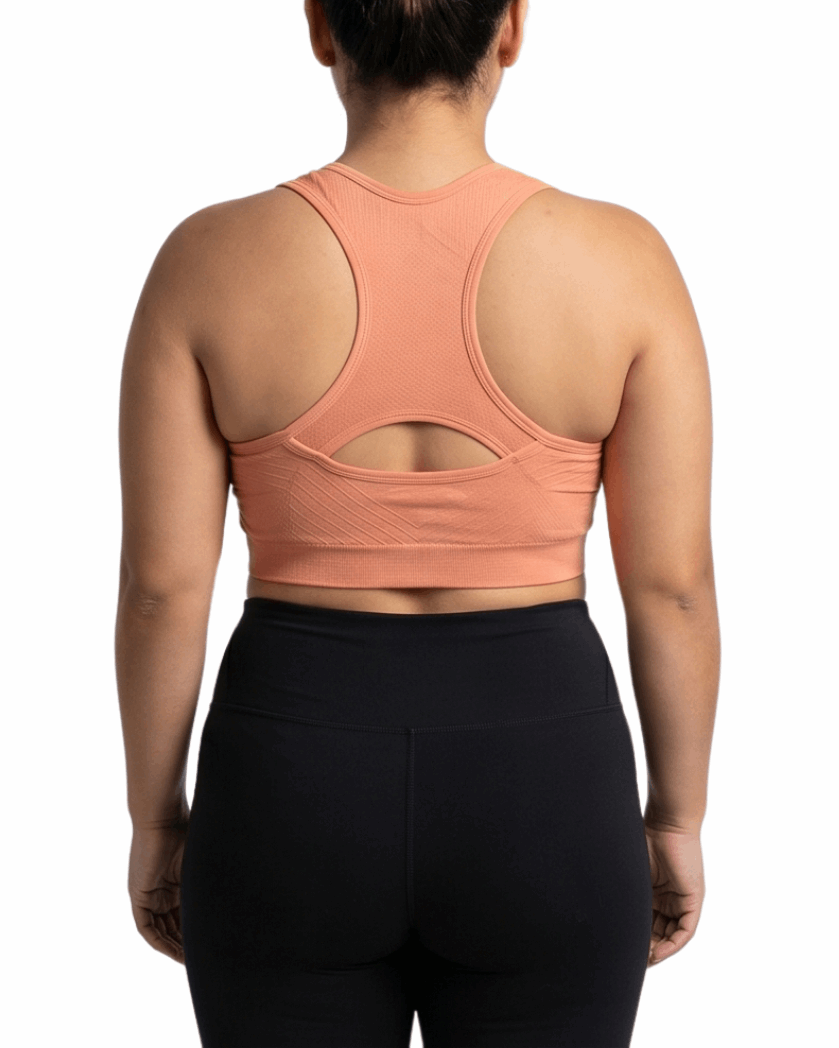 Person wearing a peach sports bra and black leggings on a white background