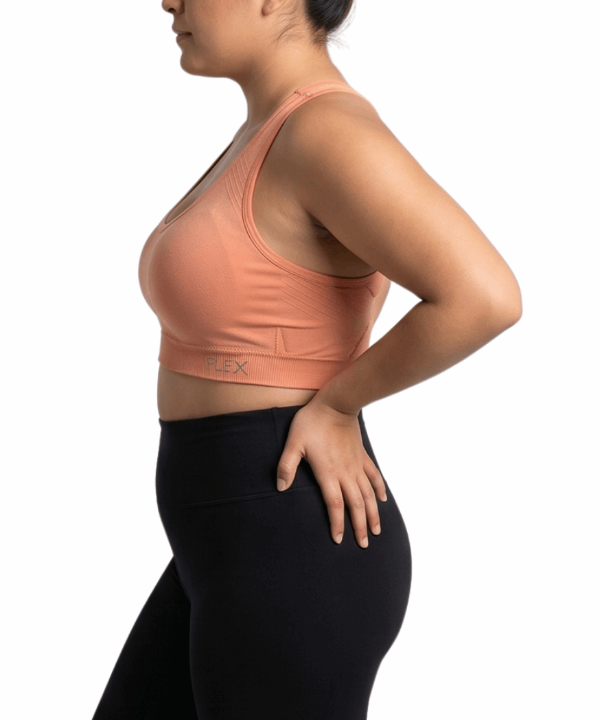 Woman wearing a peach sports bra and black leggings on a white background