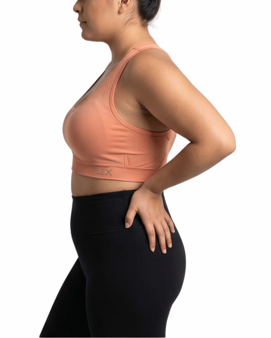 Woman wearing a peach sports bra and black leggings on a white background