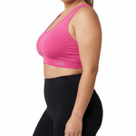 Woman wearing a pink sports bra and black leggings on a white background