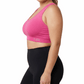 Woman wearing a pink sports bra and black leggings on a white background