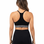 Person wearing a black sports bra with white stripes and black leggings on a white background