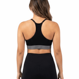 Person wearing a black sports bra with white stripes and black leggings on a white background