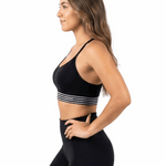 Woman wearing a black sports bra with striped design and matching leggings on a white background