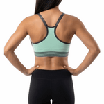 Woman wearing a green sports bra and black shorts on a white background