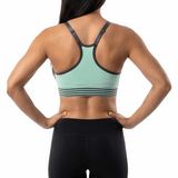 Woman wearing a green sports bra and black shorts on a white background