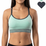 Woman wearing a green sports bra with black accents on a white background