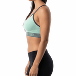 Woman wearing a green sports bra and black shorts on a white background