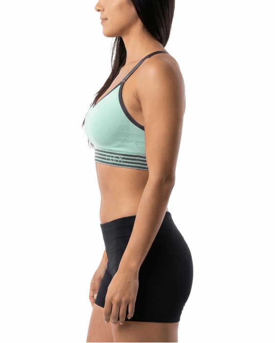 Woman wearing a green sports bra and black shorts on a white background
