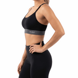Woman wearing a black sports bra and leggings on a white background