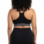 Woman wearing a black sports bra and leggings on a white background