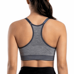Woman wearing a gray sports bra and black leggings on a white background