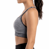 Woman wearing a gray sports bra and black leggings on a white background