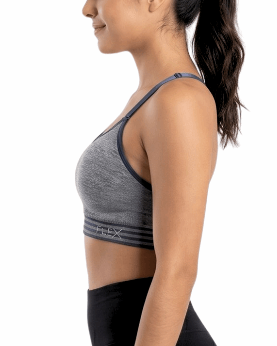 Woman wearing a gray sports bra and black leggings on a white background