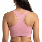 Woman wearing a pink sports bra and black leggings on a white background