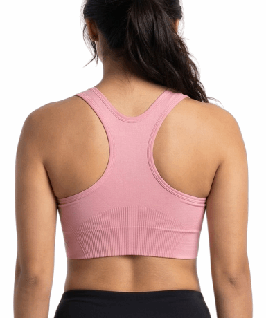 Woman wearing a pink sports bra and black leggings on a white background