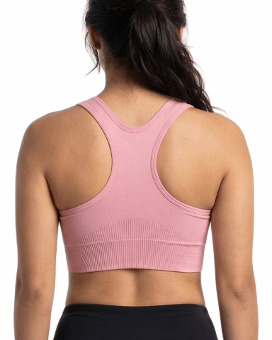 Woman wearing a pink sports bra and black leggings on a white background