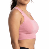 Woman wearing a pink sports bra and black leggings on a white background