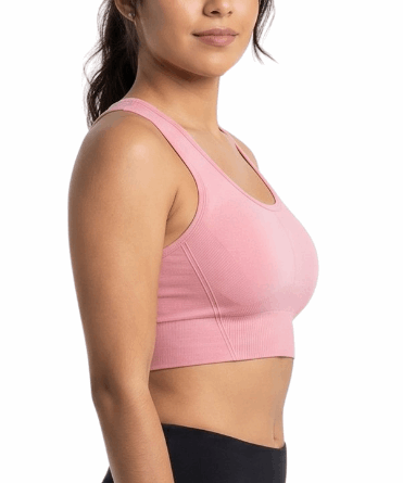 Woman wearing a pink sports bra and black leggings on a white background