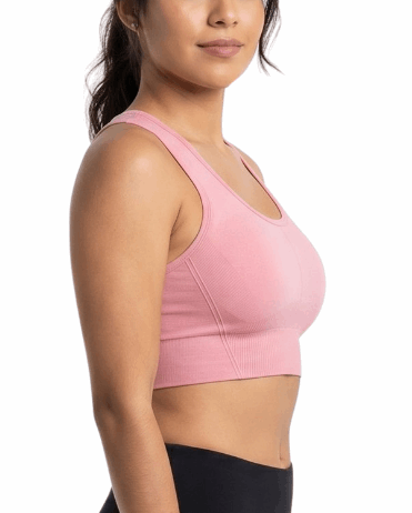 Woman wearing a pink sports bra and black leggings on a white background