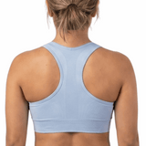 Person wearing a light blue sports bra and black leggings on a white background
