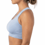 Woman wearing a light blue sports bra and black leggings on a white background
