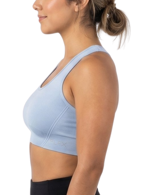 Woman wearing a light blue sports bra and black leggings on a white background
