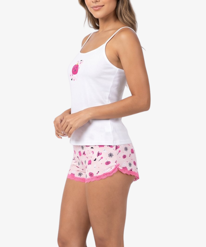 A woman modeling a white camisole tank top and matching pink patterned shorts against a plain light gray studio background.
