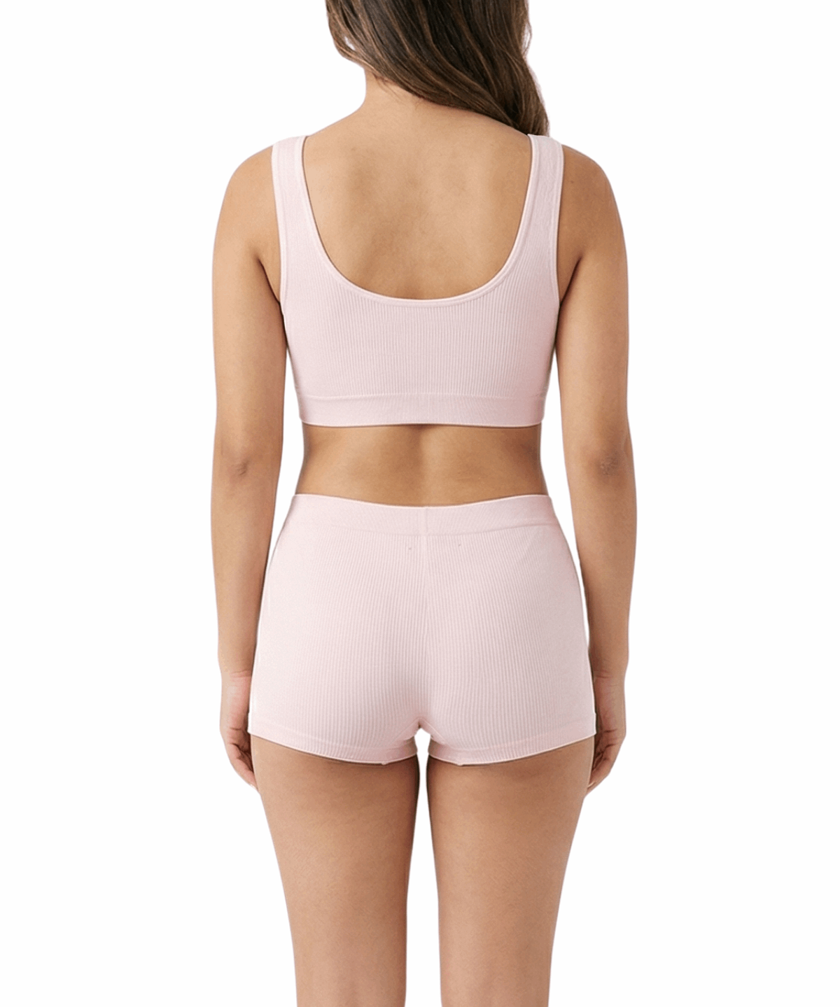 Woman wearing a pink sports bra and shorts set on a white background
