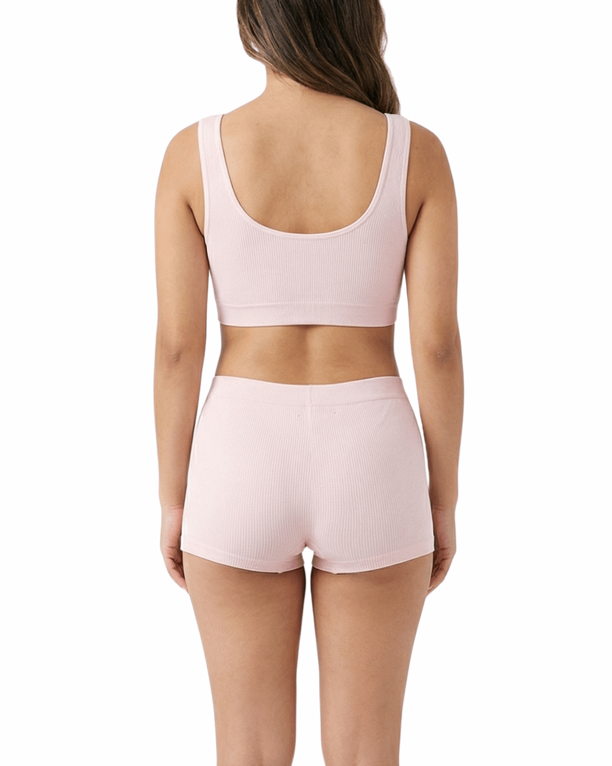Woman wearing a pink sports bra and shorts set on a white background