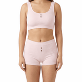 Woman wearing a pink comfort bra and shorts set on a white background